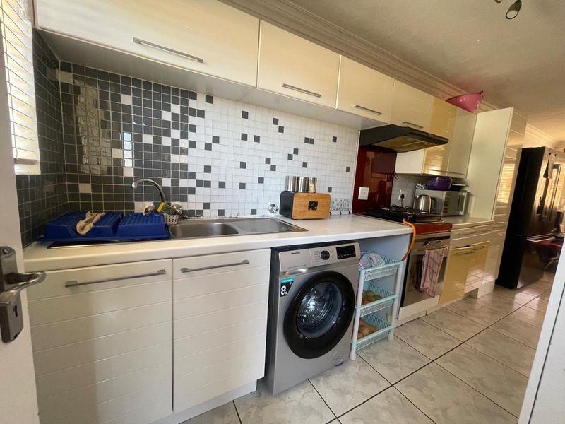 A functional kitchen featuring built-in cabinetry, a tiled backsplash, integrated oven with extractor fan, and tiled flooring.