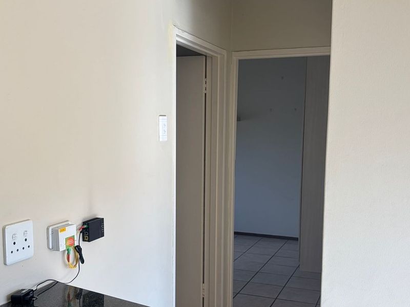 A neutral hallway area featuring tiled flooring and wall-mounted electrical and network connectivity points, leading into an adjacent room.