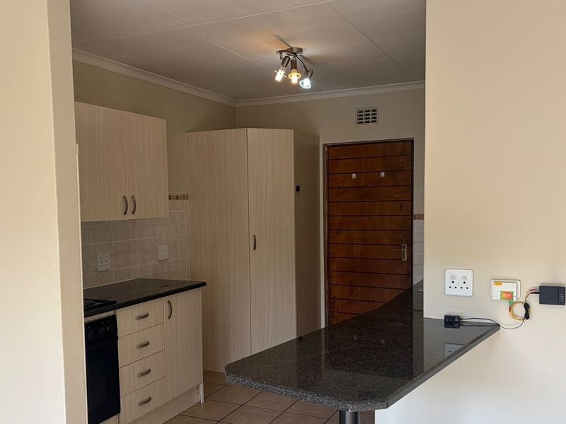 A functional kitchen featuring light-toned built-in cabinetry, granite countertops, a built-in oven, and a convenient breakfast bar counter.