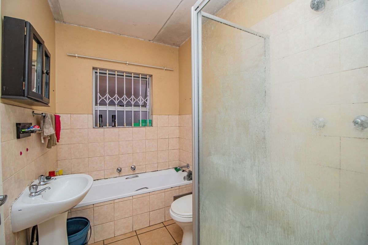 A functional bathroom featuring a pedestal basin, built-in bathtub, and a separate shower enclosure with tiled finishes.