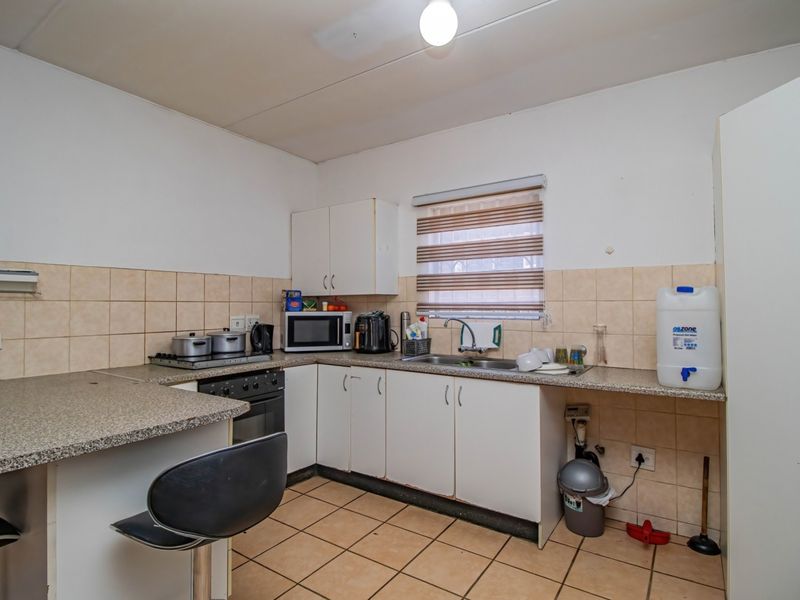 Functional kitchen featuring built-in cabinetry, laminate countertops, tiled backsplash, and tiled flooring, offering a practical layout for daily meal preparation.