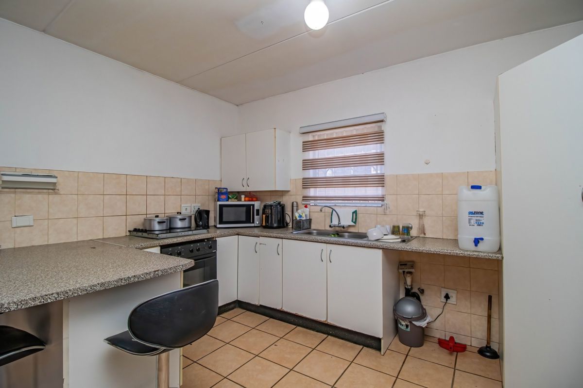 Functional kitchen featuring built-in cabinetry, laminate countertops, tiled backsplash, and tiled flooring, offering a practical layout for daily meal preparation.