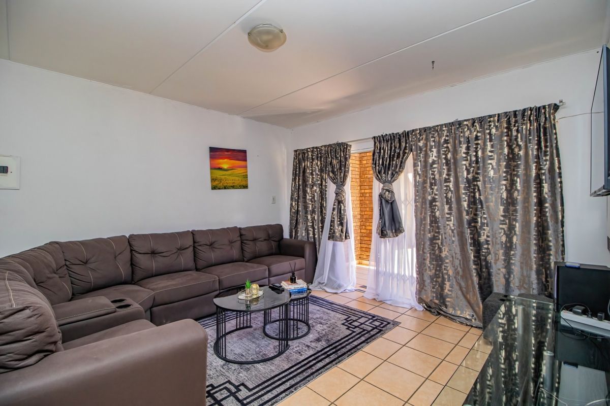 A living room featuring tiled flooring and a sliding glass door providing access to an outdoor area.