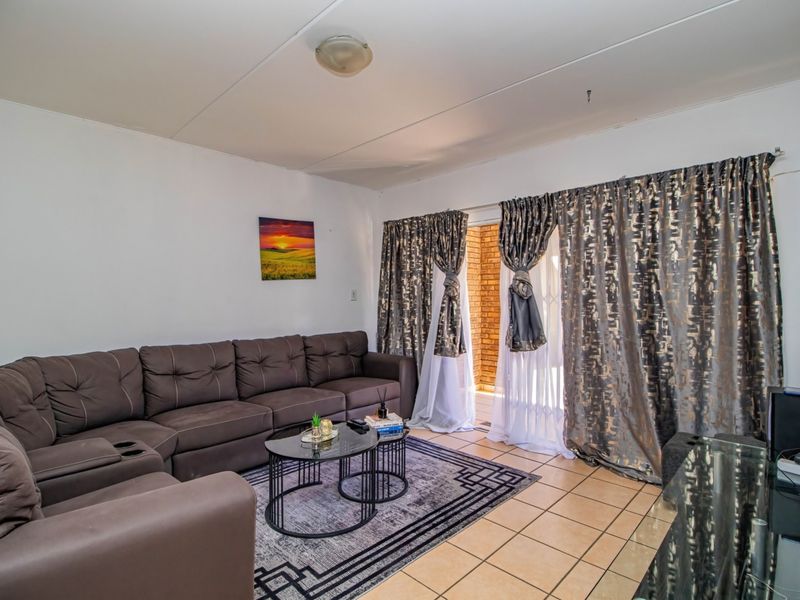 A living room featuring tiled flooring and a sliding glass door providing access to an outdoor area.