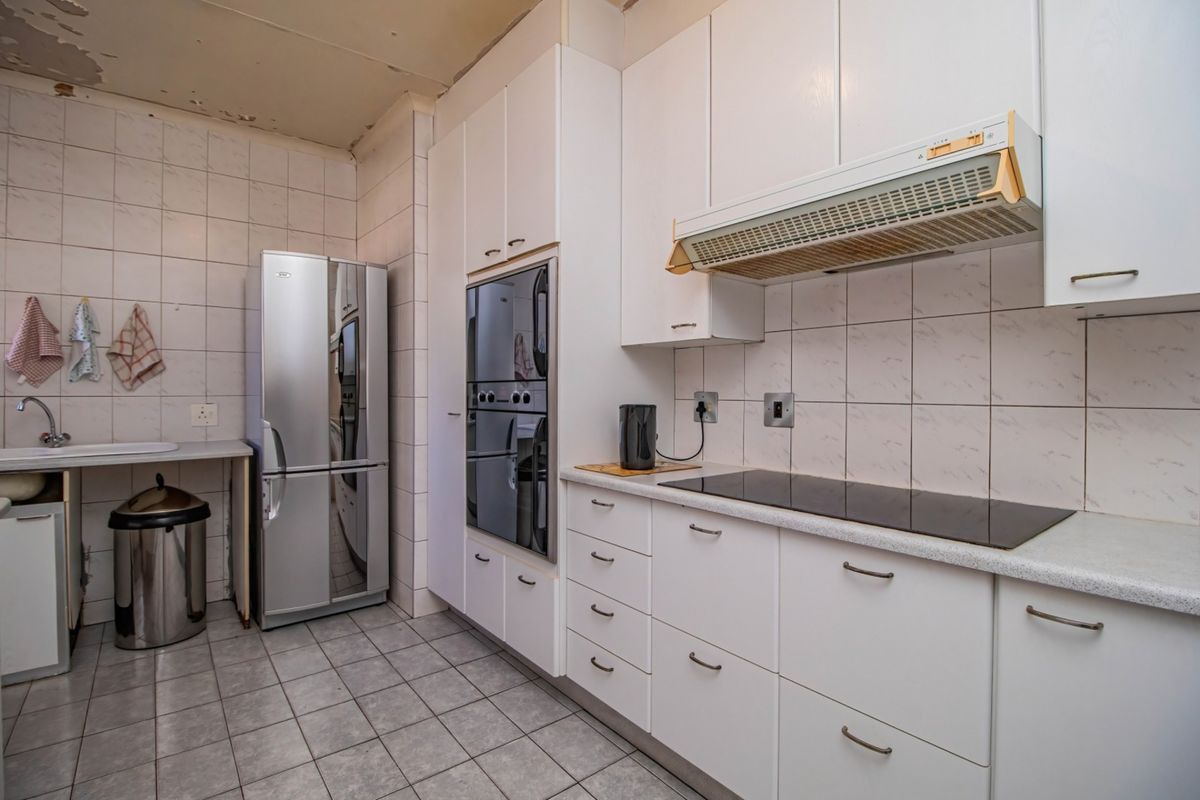 A functional kitchen featuring built-in cabinetry, an electric hob, and an oven, requiring ceiling repairs and cosmetic updates to modernize the space.