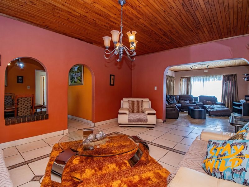 Open plan living area featuring ceramic tile flooring, a timber tongue and groove ceiling, and distinctive arched wall openings connecting to adjacent spaces.