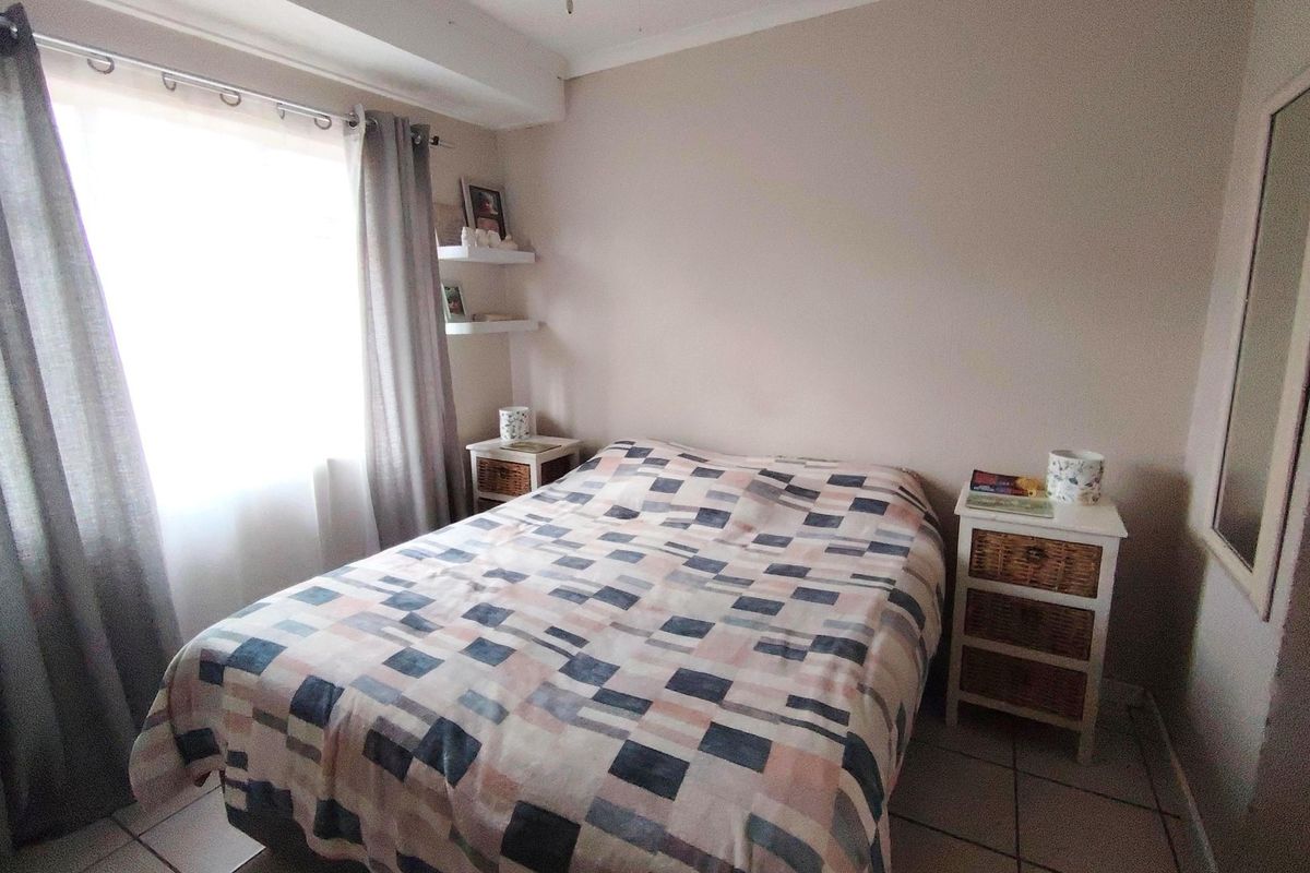 A functional bedroom featuring tiled flooring, a ceiling fan, and built-in floating wall shelves, providing a neutral base for personalization.