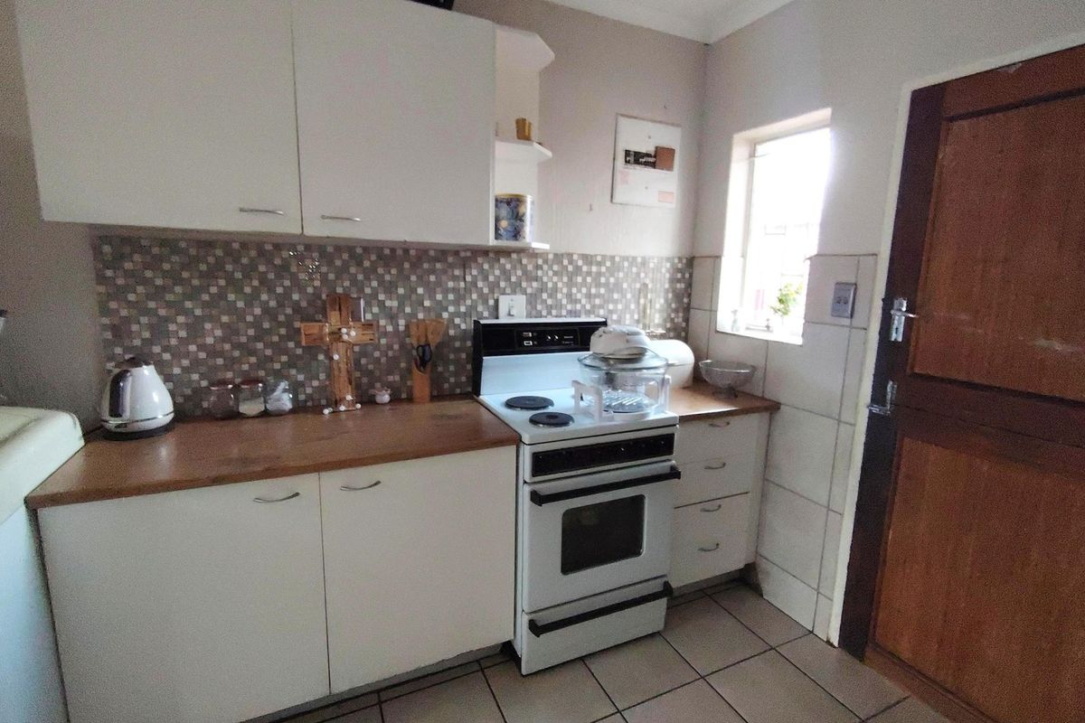 A functional kitchen featuring white cabinetry, a wooden countertop, mosaic tile backsplash, and a freestanding stove with tiled flooring.
