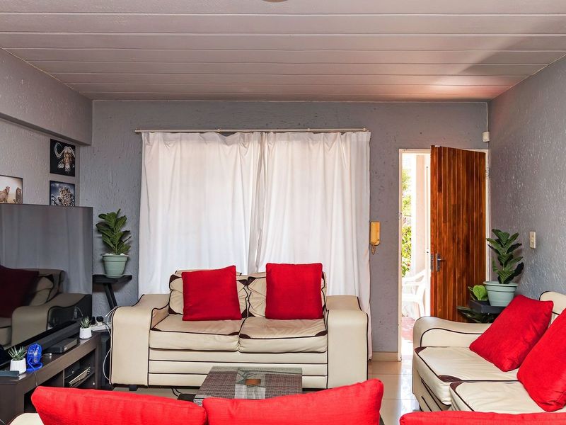 A comfortable living room featuring tiled flooring, textured walls, and direct access to an outdoor area through a timber door.