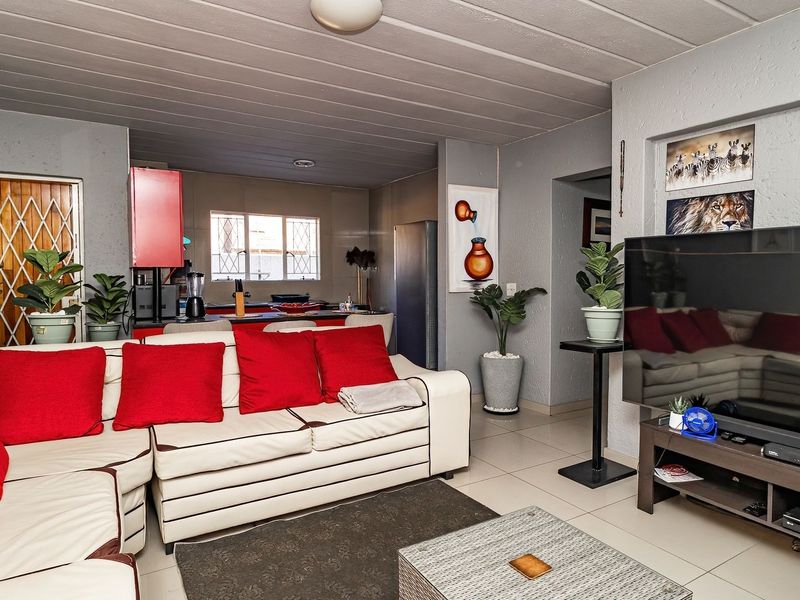 Open-plan living area featuring tiled flooring and a connected kitchen space with built-in cabinetry, providing a functional layout for modern apartment living.