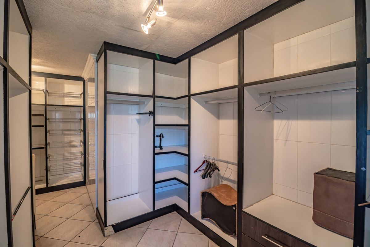 A spacious walk-in closet featuring extensive built-in shelving, hanging rails, and tiled flooring, providing ample storage space.