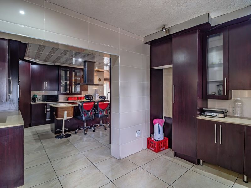 A spacious kitchen featuring dark wood cabinetry, tiled flooring, and a central island with an integrated extractor fan, offering ample storage and prep space.