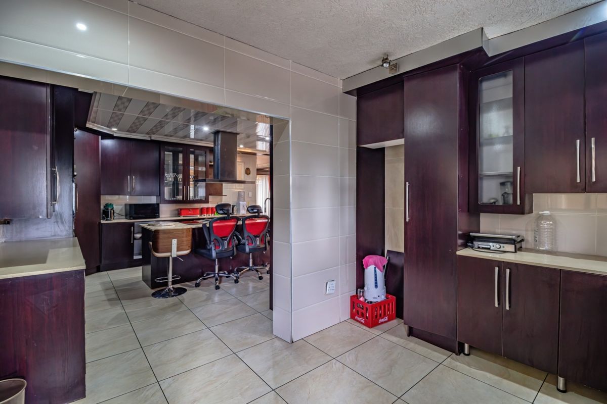 A spacious kitchen featuring dark wood cabinetry, tiled flooring, and a central island with an integrated extractor fan, offering ample storage and prep space.
