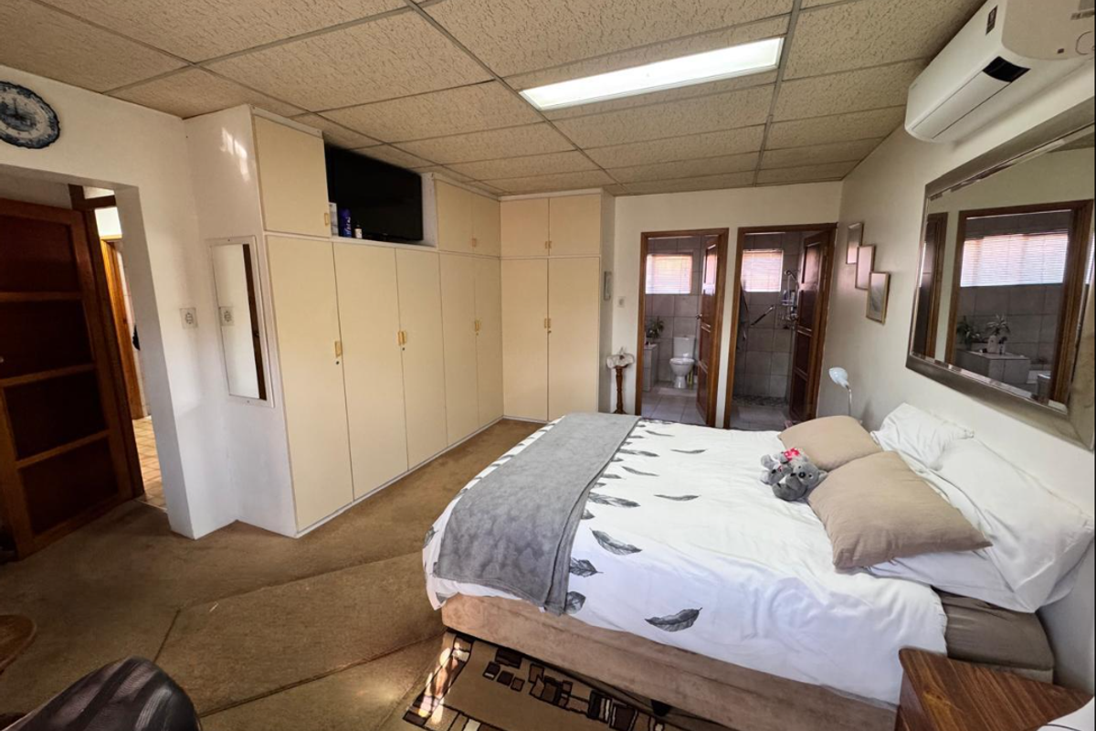 Spacious bedroom featuring extensive built-in cabinetry, a drop ceiling with integrated lighting, and an en-suite bathroom.