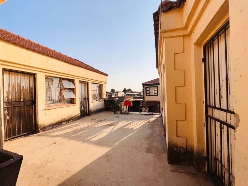 An open-air concrete patio area situated between building wings, featuring security gates and weathered exterior finishes in need of maintenance.