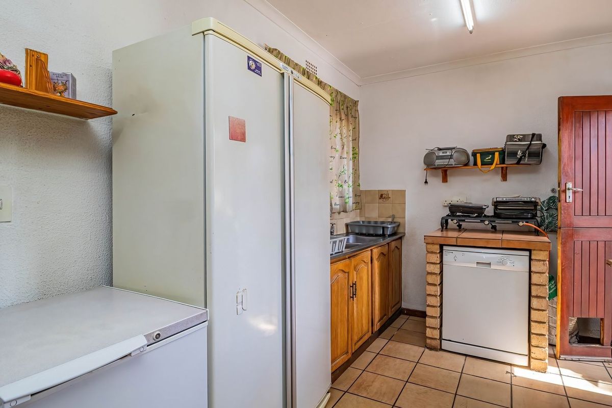 A functional kitchen featuring wooden cabinetry, tiled flooring, and a brick-base counter area, offering potential for modernization and aesthetic updates.