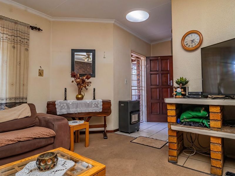 A living room featuring a built-in brick television stand, tiled entrance area, and direct access to the front door.