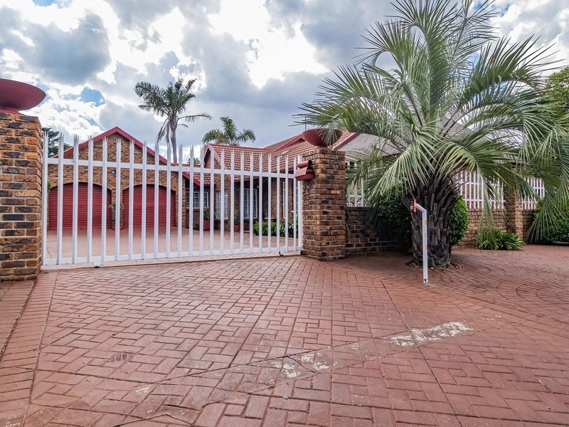 Front exterior view featuring a brick paved driveway, secure gated entrance, and double garage with a tiled roof.