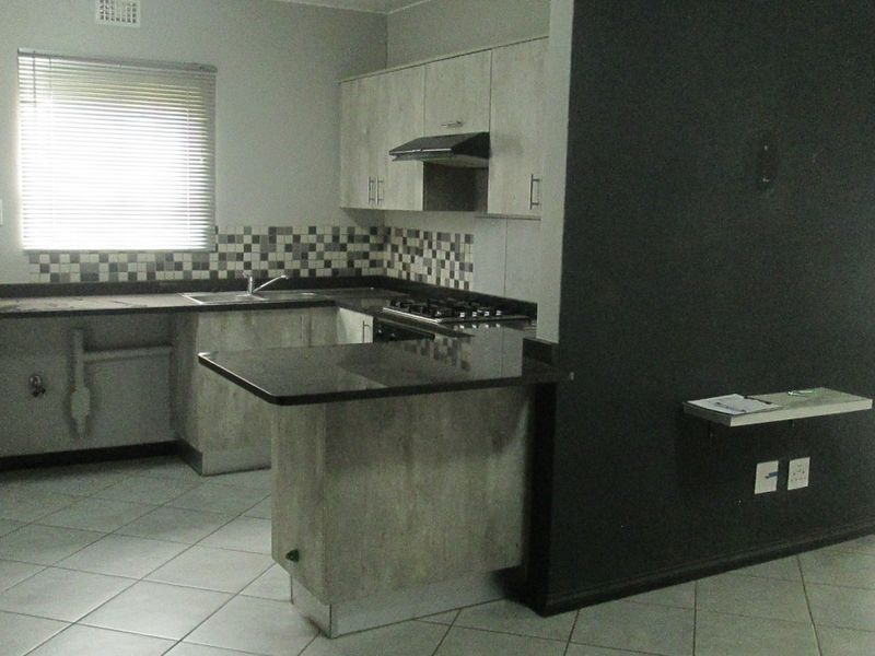 Open-plan kitchen featuring built-in cabinetry, granite countertops, a gas hob, and a breakfast nook, seamlessly flowing into the living area.