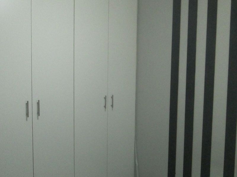 A bedroom featuring white built-in cupboards and a decorative striped accent wall.