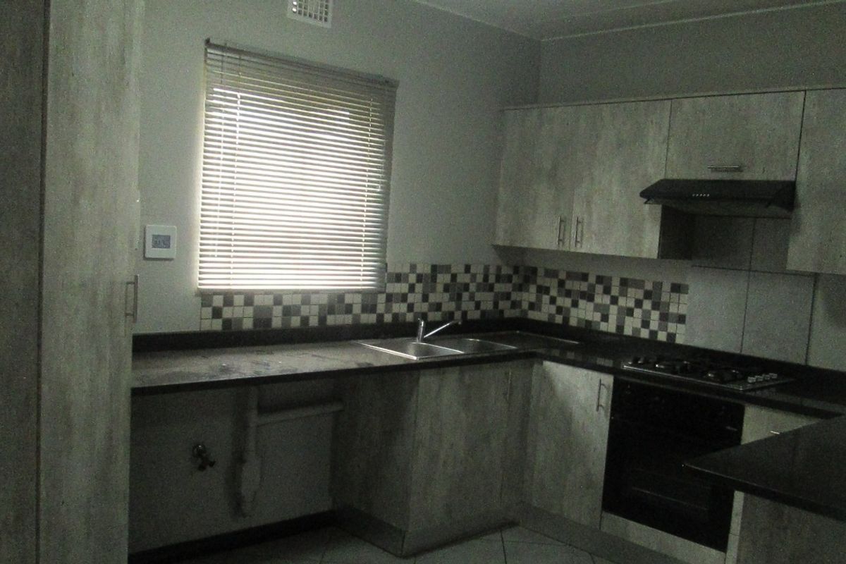 A functional kitchen featuring built-in cabinetry, dark laminate countertops, a double basin sink, and integrated oven with gas hob.