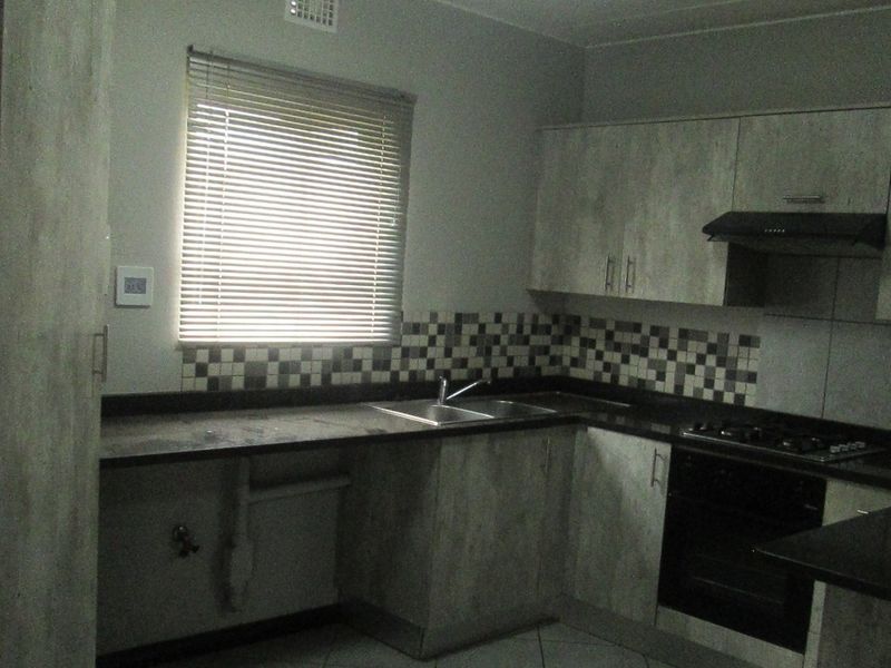 A functional kitchen featuring built-in cabinetry, dark laminate countertops, a double basin sink, and integrated oven with gas hob.