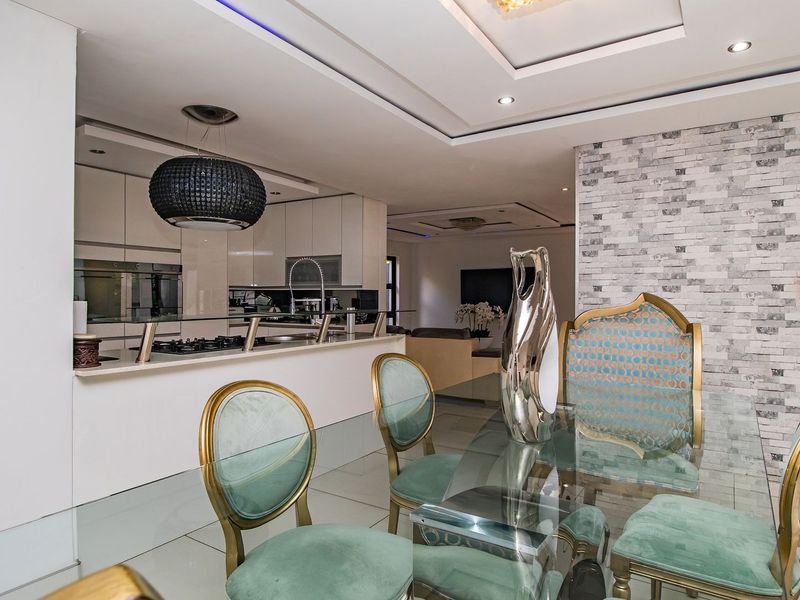 Modern open-plan living and dining area featuring a sleek kitchen with built-in appliances, stone feature wall, and elegant recessed ceiling lighting.