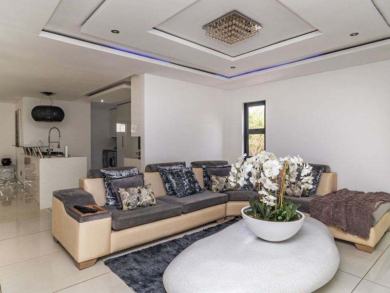 Spacious open-plan living area featuring modern porcelain tiling, a recessed ceiling with ambient lighting, and a sleek kitchen island with integrated fixtures.