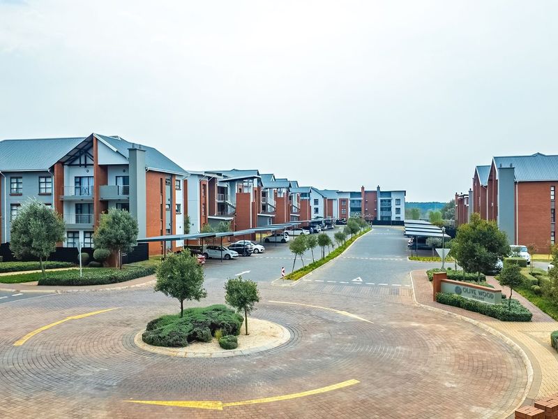 Aerial view of a modern townhouse complex featuring paved driveways, covered parking bays, and well-maintained landscaped grounds.