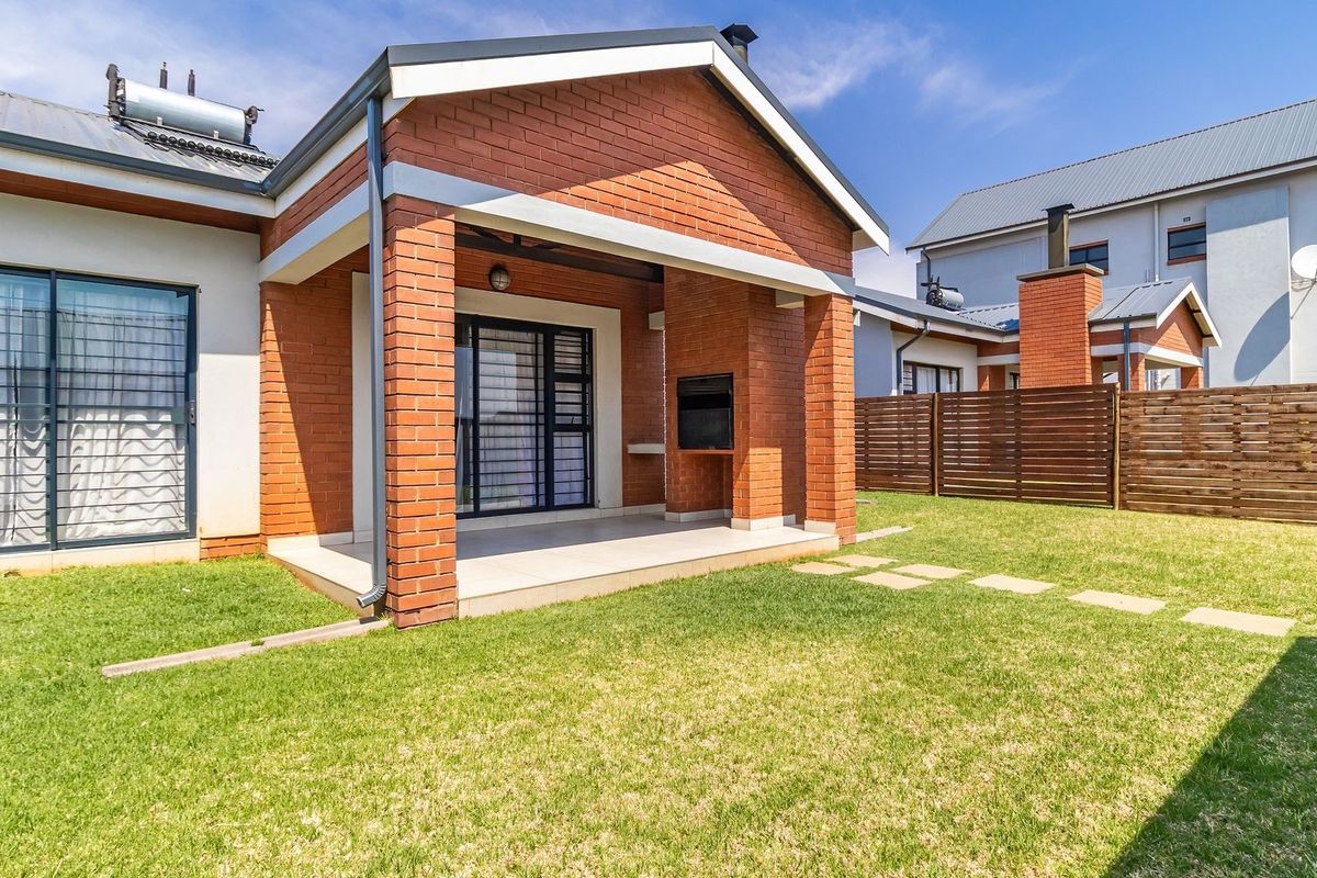 Rear view of the townhouse featuring a covered patio with a built-in braai, private garden, and solar water heating system.