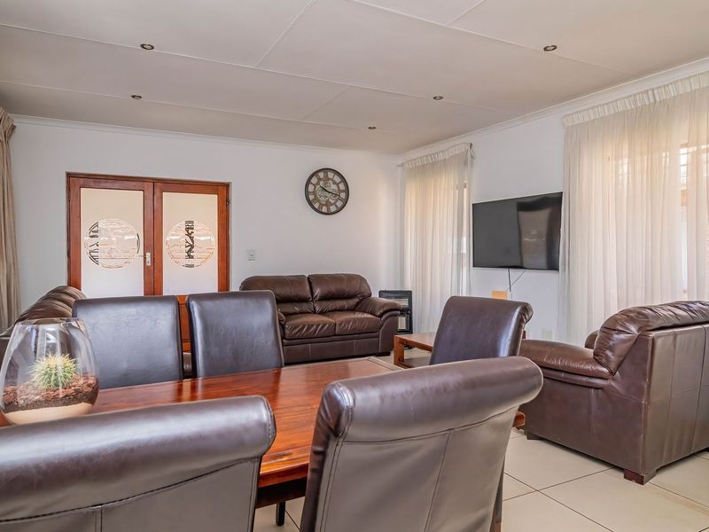 Open plan living and dining area featuring tiled flooring, recessed ceiling lighting, and double glass panel doors leading to the exterior.