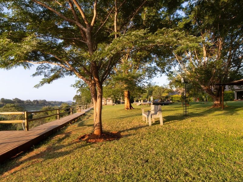 A well-maintained garden area featuring a wooden deck walkway, timber fencing, and mature trees overlooking the surrounding landscape.