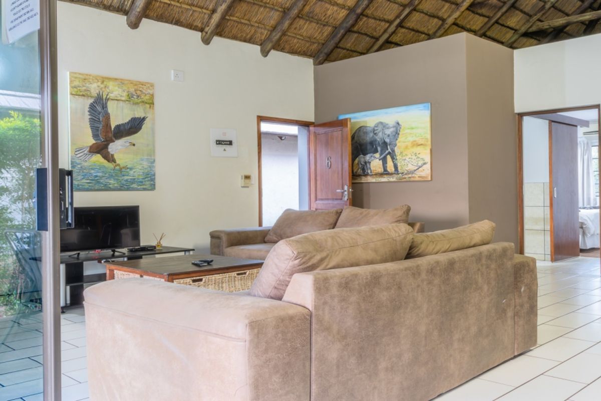 A living room area featuring a traditional thatched roof with exposed timber rafters and tiled flooring, providing a rustic lodge atmosphere.