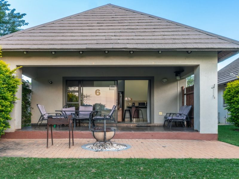 A covered patio area featuring tiled roofing and sliding glass doors, leading out to a brick-paved outdoor space with a fire pit.