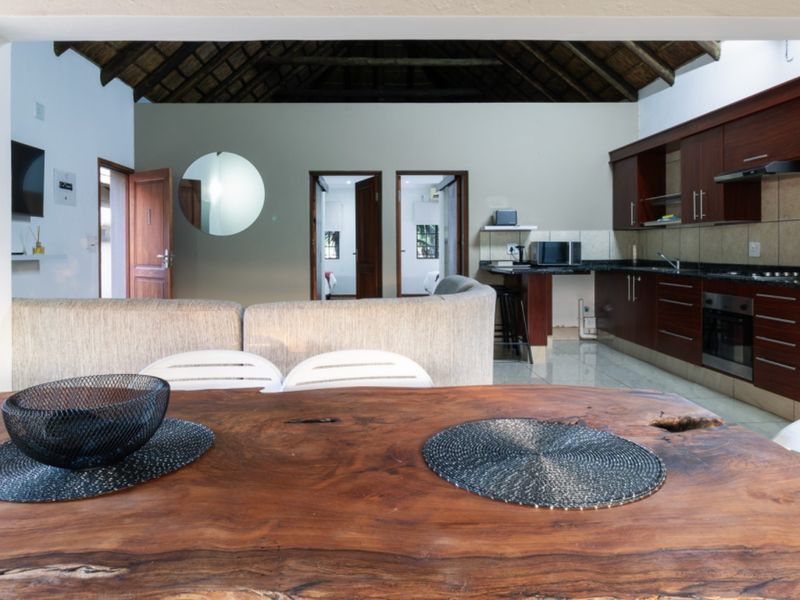 Open-plan living and kitchen area featuring a high thatched ceiling with exposed rafters, dark wood cabinetry, and granite countertops.