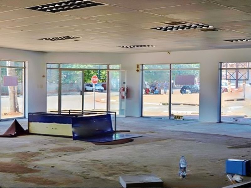 Spacious open-plan retail unit featuring large glass storefront windows, suspended ceilings with recessed lighting, and concrete flooring, suitable for various commercial business applications.