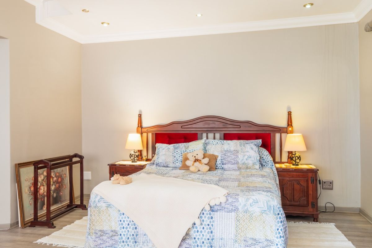 A well-maintained bedroom featuring neutral wall tones, recessed ceiling lighting, and light-colored wood-look flooring.