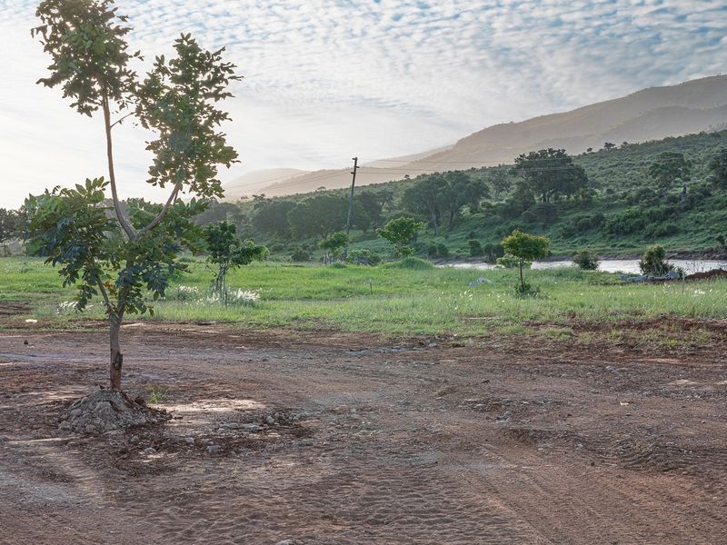 A scenic view of the vacant residential land featuring natural vegetation, a dirt access path, and distant mountain landscape.