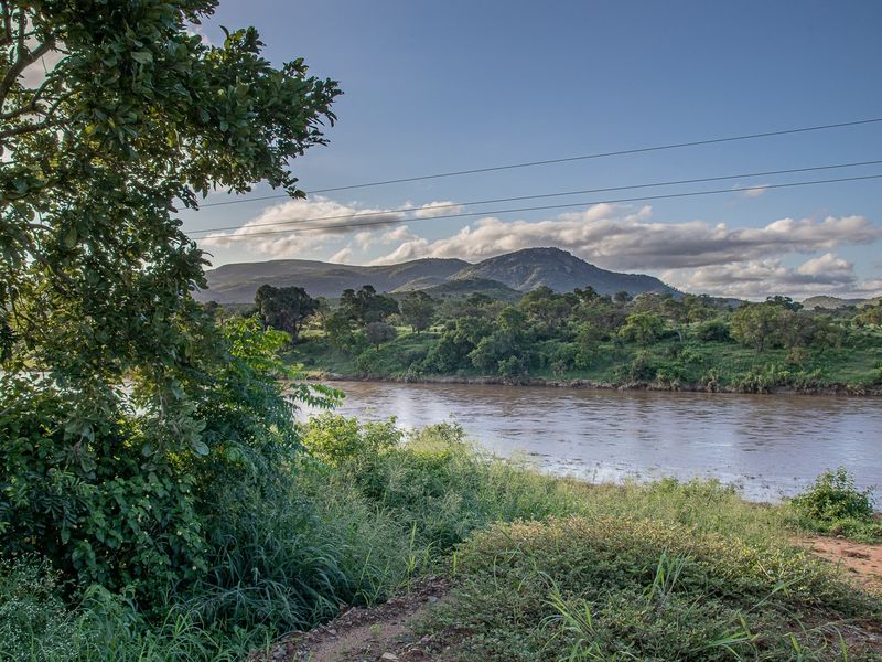 A scenic view of a river flowing through a natural landscape with lush vegetation and mountains in the background.
