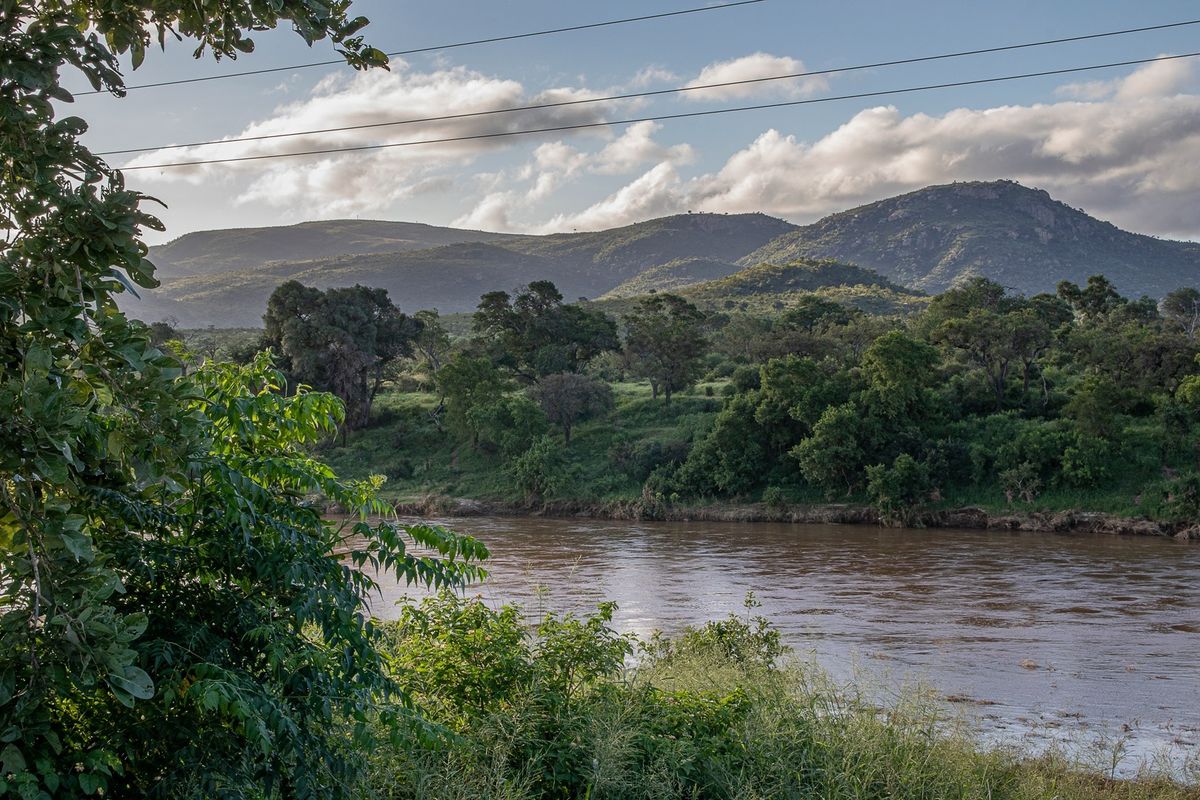 A scenic view of a river flowing through a natural landscape with mountains in the background.