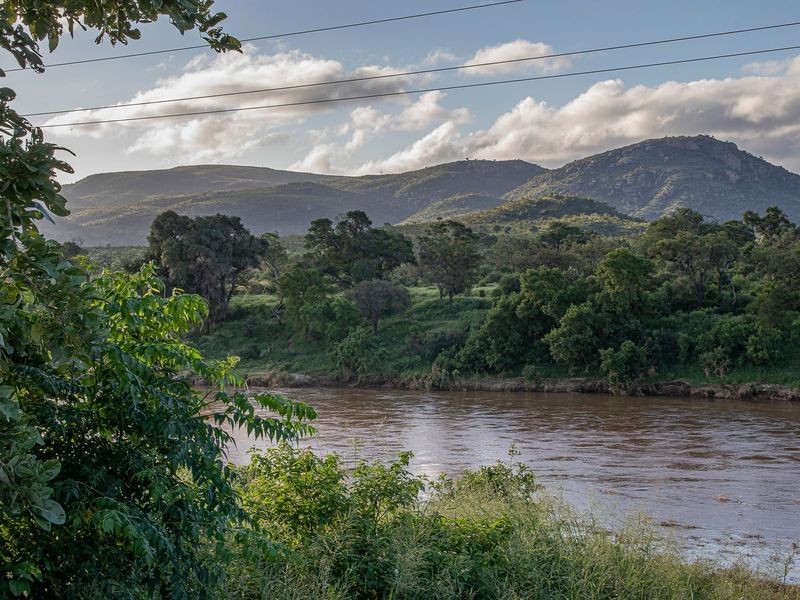 A scenic view of a river flowing through a natural landscape with mountains in the background.