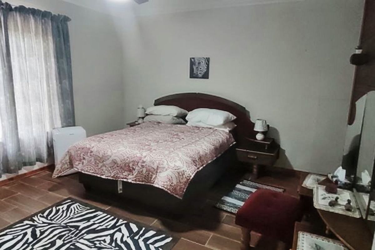A bedroom featuring tiled flooring and large windows with curtains, providing a functional and comfortable living space.