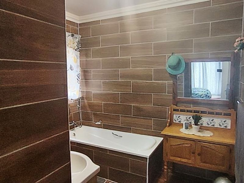A bathroom featuring wood-look wall tiles, a built-in bathtub, and a wooden vanity cabinet.