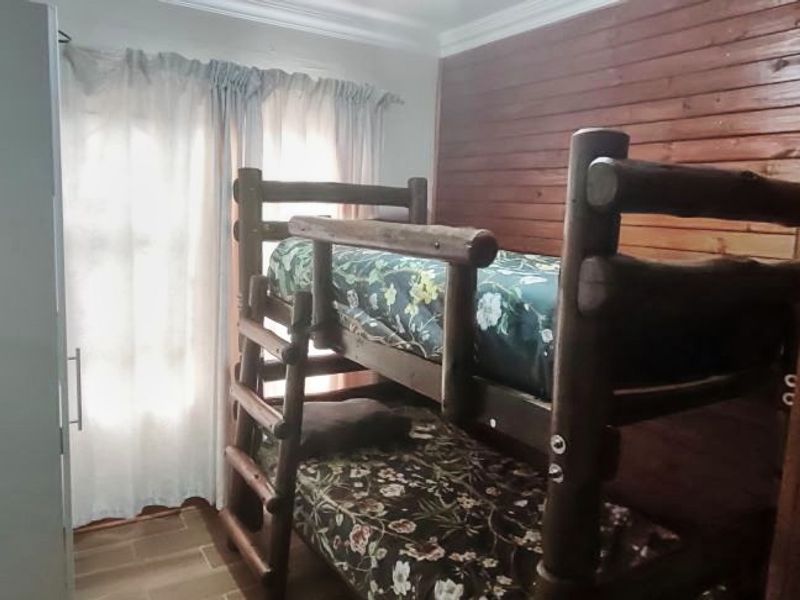A bedroom featuring timber wall cladding, tiled flooring, and a built-in cupboard, offering a rustic aesthetic.