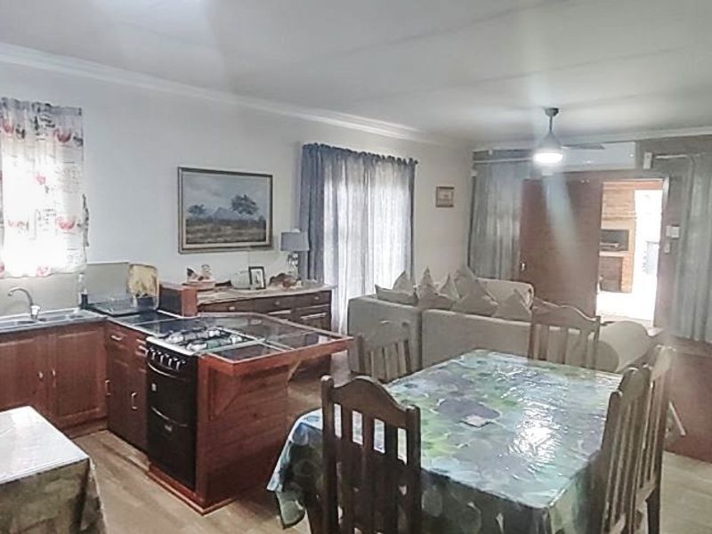 Spacious open-plan living area featuring a functional kitchen with built-in cabinetry, oven, and hob, seamlessly flowing into the dining and lounge space.
