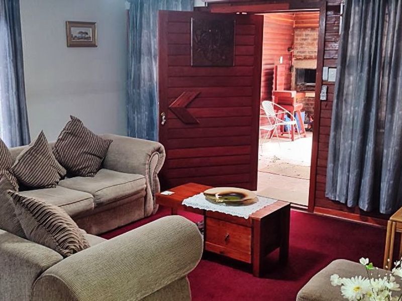 A living room featuring timber wall paneling, carpeted flooring, and sliding glass doors leading to an outdoor area.