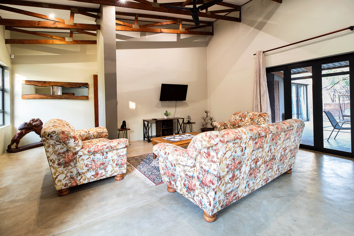 Spacious living room featuring high vaulted ceilings with exposed timber trusses, polished concrete floors, and large glass sliding doors leading to the patio.