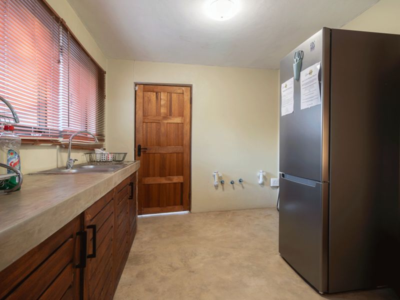 Functional laundry room featuring a concrete countertop, stainless steel sink, wooden cabinetry, and dedicated plumbing connections for appliances.