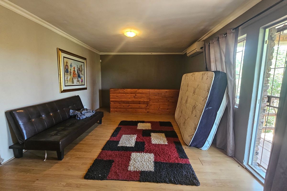 A living room featuring laminate flooring, a wall-mounted air conditioning unit, and sliding glass doors providing access to an outdoor area.