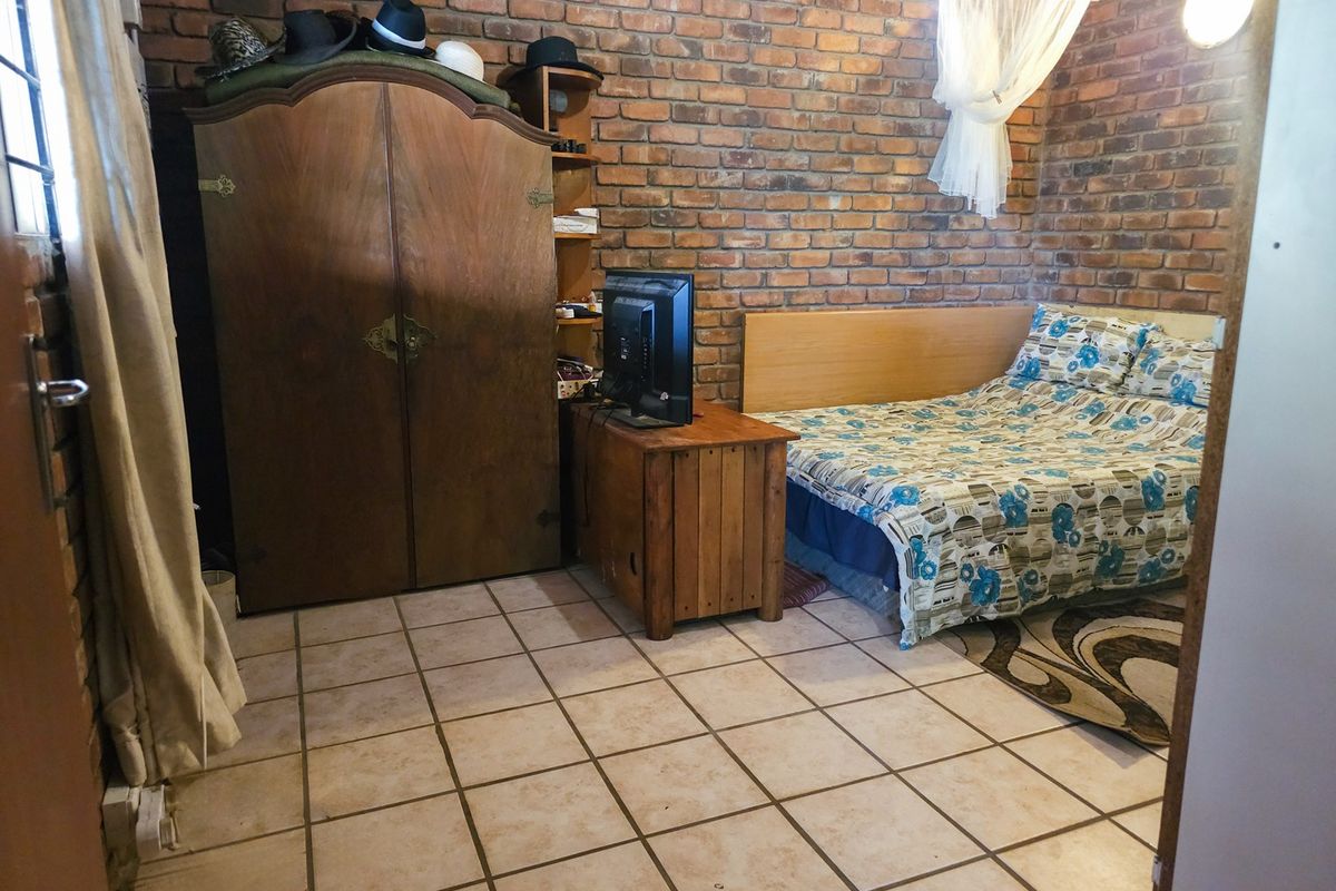 A bedroom featuring exposed brick walls and tiled flooring, providing a rustic aesthetic with built-in structural elements.